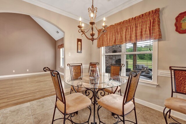 dining room with an inviting chandelier, ornamental molding, a fireplace, arched walkways, and light tile patterned floors