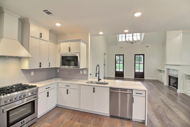 235 Freedom Ln, Rossville, TN 38066 - kitchen featuring visible vents, a peninsula, wall chimney exhaust hood, a sink, and stainless steel appliances