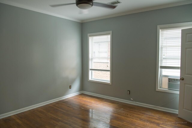 empty room with crown molding, dark wood finished floors, a ceiling fan, baseboards, and visible vents