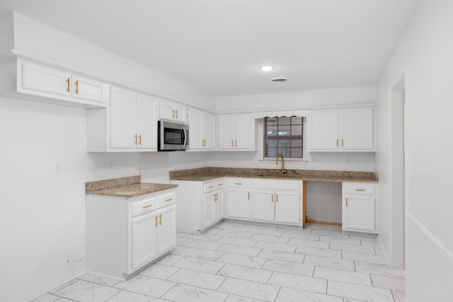 kitchen featuring marble finish floor, recessed lighting, stainless steel microwave, white cabinets, and a sink