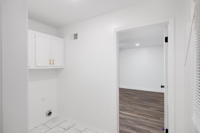 clothes washing area featuring baseboards, hookup for an electric dryer, cabinet space, and visible vents