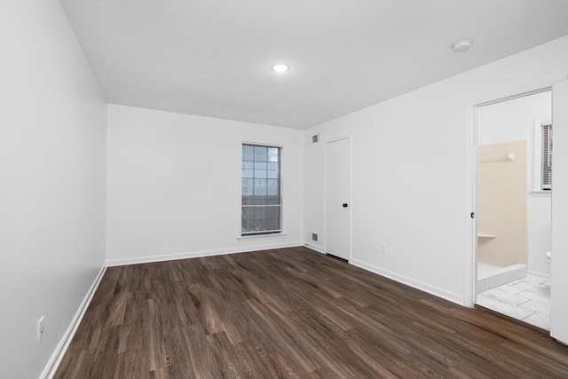 empty room featuring recessed lighting, baseboards, and dark wood-type flooring