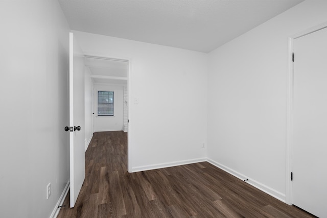 unfurnished room with baseboards and dark wood finished floors