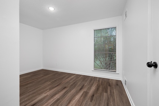 spare room with a textured ceiling, baseboards, dark wood finished floors, and recessed lighting