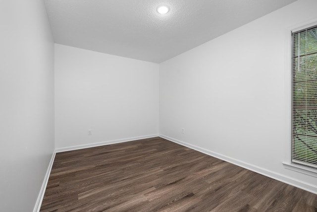 empty room with dark wood-style flooring, baseboards, and a textured ceiling