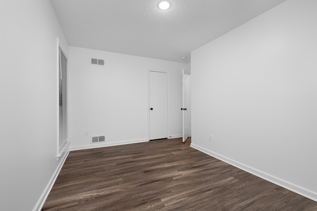 unfurnished room with baseboards, dark wood finished floors, and visible vents