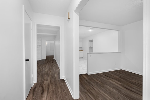 hall with dark wood-style flooring and baseboards