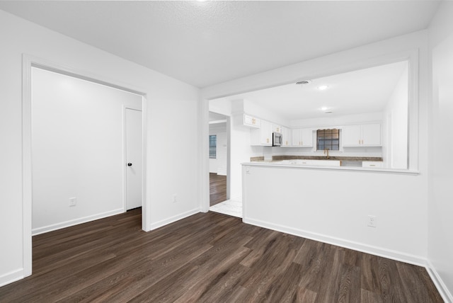 unfurnished living room featuring a sink, baseboards, dark wood finished floors, and visible vents