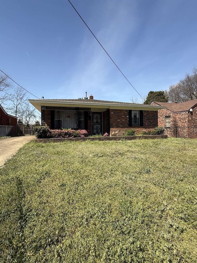 rear view of house with a lawn, fence, and brick siding