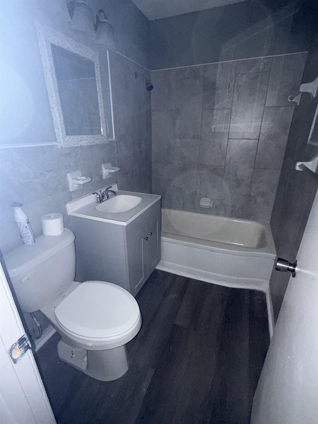 bathroom featuring tile walls, wood finished floors, vanity, toilet, and bathing tub / shower combination