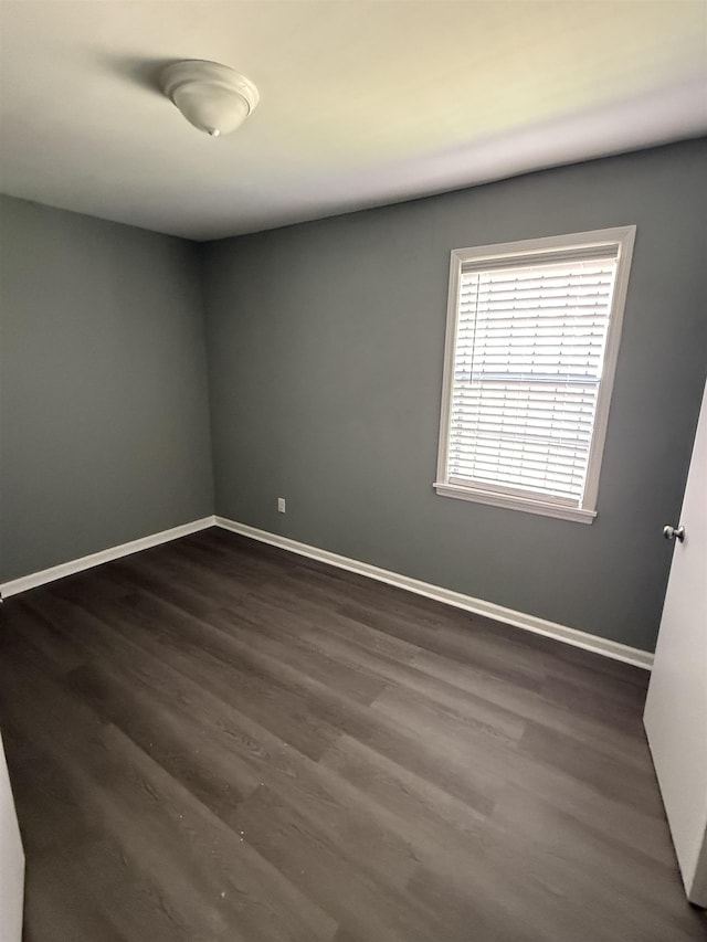 unfurnished room featuring baseboards and dark wood finished floors