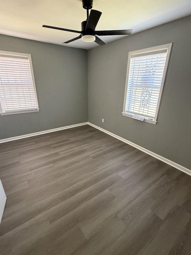 empty room with ceiling fan, dark wood-style floors, and baseboards