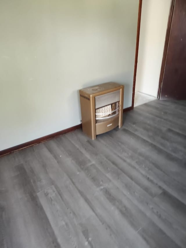 interior space with heating unit, baseboards, and wood finished floors