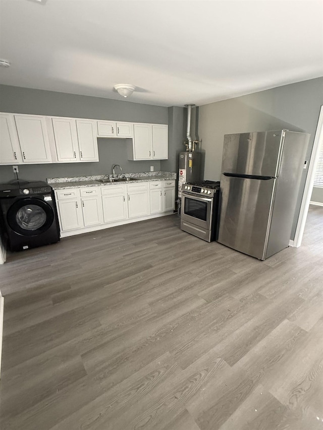kitchen with washer / clothes dryer, appliances with stainless steel finishes, light stone counters, white cabinets, and light wood-style flooring