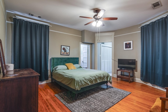 bedroom featuring a ceiling fan, visible vents, and wood finished floors