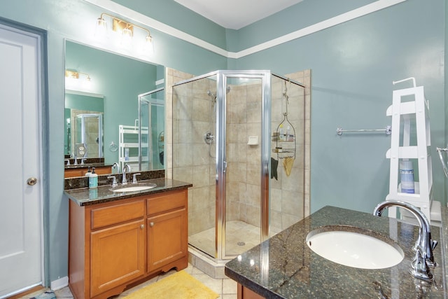 full bath with tile patterned flooring, a sink, two vanities, and a stall shower
