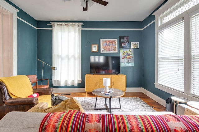 living room featuring baseboards, ceiling fan, and wood finished floors