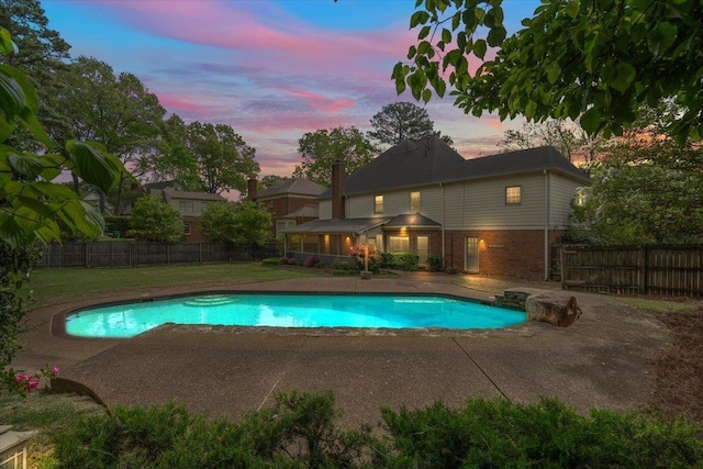pool at dusk featuring a fenced in pool, a patio, a lawn, and a fenced backyard