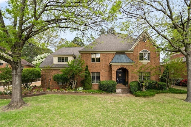 traditional home featuring brick siding, a shingled roof, and a front lawn