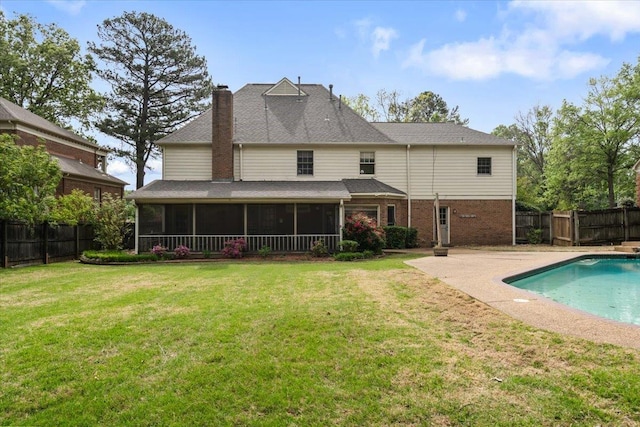rear view of property with a fenced in pool, a chimney, a fenced backyard, and a sunroom