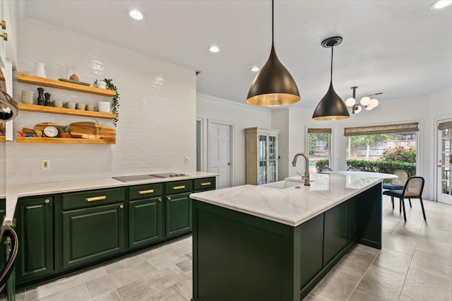 kitchen with open shelves, black electric cooktop, a sink, green cabinets, and an island with sink