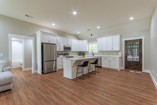 50 Melrose Cv, Savannah, TN 38372 - kitchen featuring appliances with stainless steel finishes, wood finished floors, open floor plan, and a breakfast bar