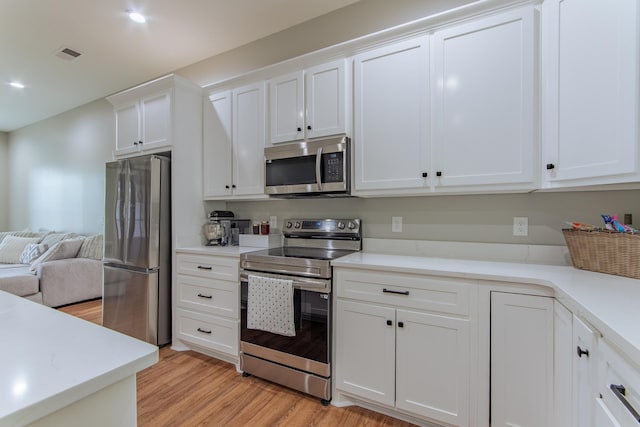 50 Melrose Cv, Savannah, TN 38372 - kitchen with light wood finished floors, visible vents, white cabinetry, light countertops, and appliances with stainless steel finishes