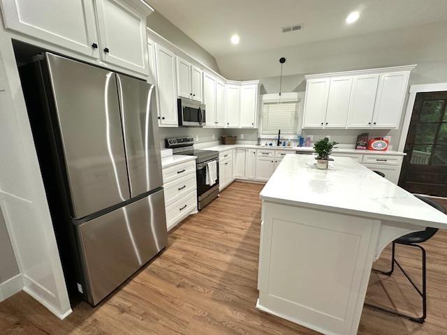 50 Melrose Cv, Savannah, TN 38372 - kitchen with a sink, stainless steel appliances, visible vents, a kitchen bar, and white cabinets