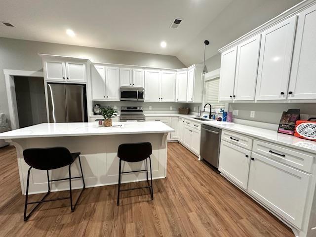 50 Melrose Cv, Savannah, TN 38372 - kitchen featuring a center island, a sink, white cabinetry, wood finished floors, and appliances with stainless steel finishes