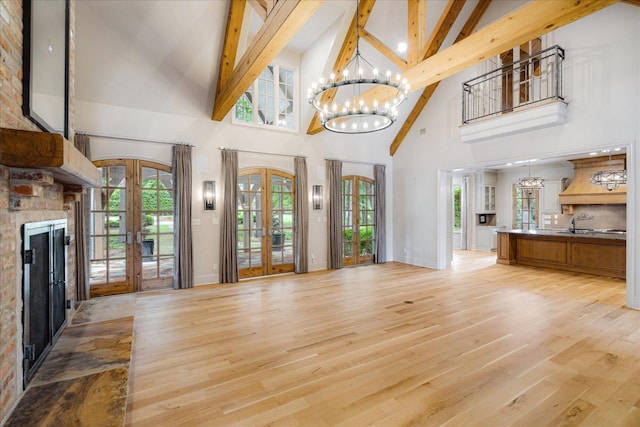 294 Dubray Manor Dr, Collierville, TN 38017 - unfurnished living room with an inviting chandelier, beam ceiling, high vaulted ceiling, light wood-style flooring, and french doors