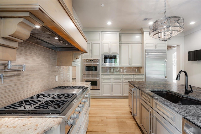 294 Dubray Manor Dr, Collierville, TN 38017 - kitchen featuring backsplash, a sink, premium range hood, light wood finished floors, and stainless steel appliances