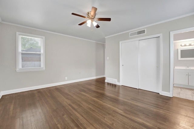 unfurnished bedroom featuring crown molding, visible vents, wood finished floors, and a closet