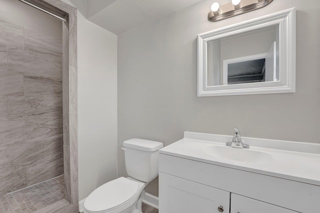 full bath featuring vanity, a tile shower, and toilet