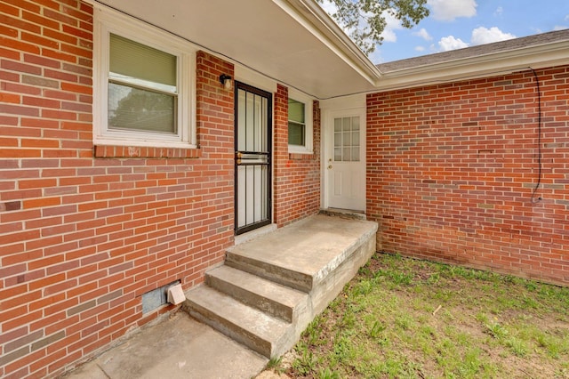 property entrance featuring brick siding and crawl space