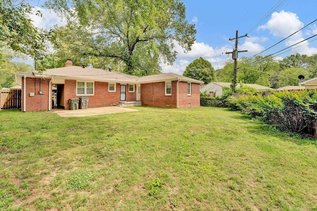 rear view of property featuring fence, a chimney, a lawn, and brick siding