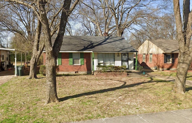 ranch-style house with a chimney, roof with shingles, a front yard, a carport, and brick siding