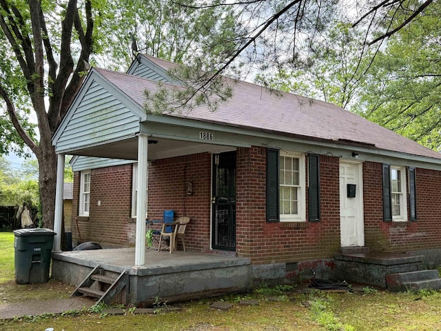 back of property featuring brick siding, crawl space, a porch, and roof with shingles