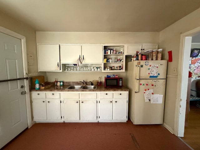 kitchen featuring dark countertops, open shelves, a sink, white cabinets, and freestanding refrigerator