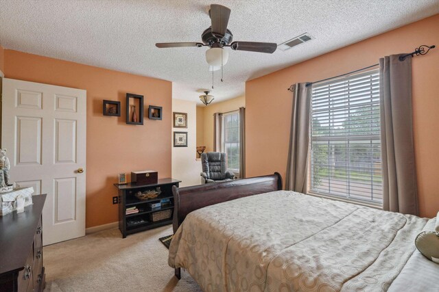 bedroom with multiple windows, light carpet, a textured ceiling, and visible vents