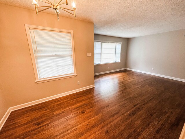 1439 Woodston Rd, Memphis, TN 38117 - spare room featuring an inviting chandelier, baseboards, dark wood finished floors, and a textured ceiling