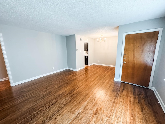 1439 Woodston Rd, Memphis, TN 38117 - unfurnished living room with dark wood-style flooring, a textured ceiling, a chandelier, and baseboards