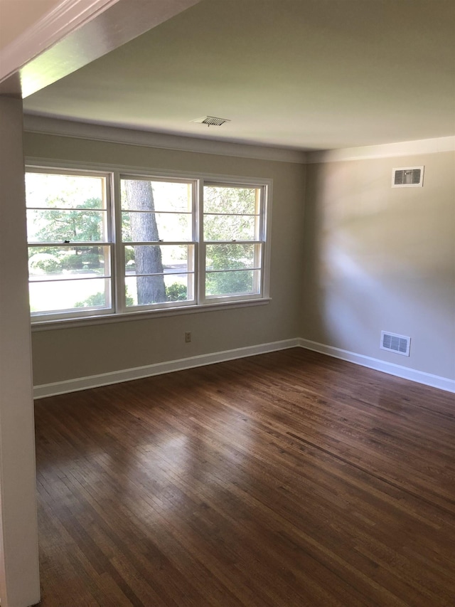 spare room with baseboards, dark wood-style floors, and visible vents