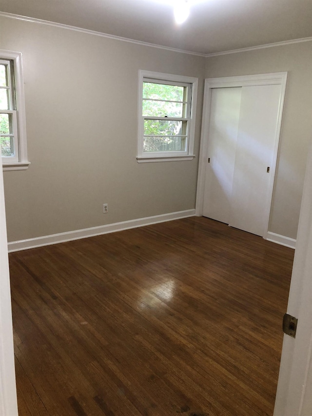 spare room featuring baseboards, plenty of natural light, ornamental molding, and dark wood-style floors