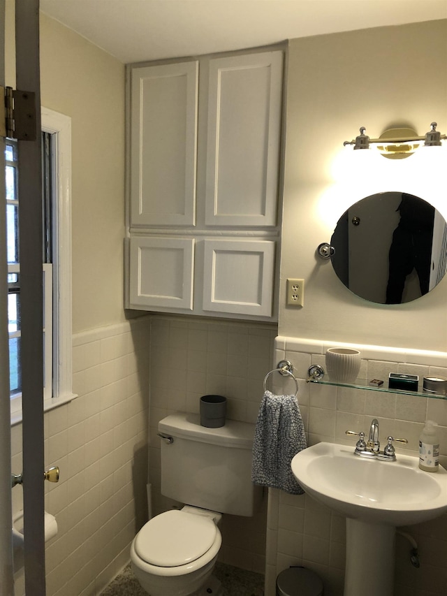 bathroom featuring wainscoting, toilet, and tile walls