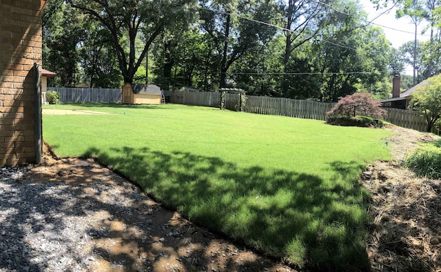 view of yard featuring an outdoor structure, a fenced backyard, and a storage unit