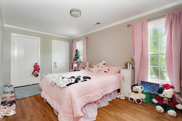 bedroom featuring ornamental molding, light wood finished floors, and visible vents