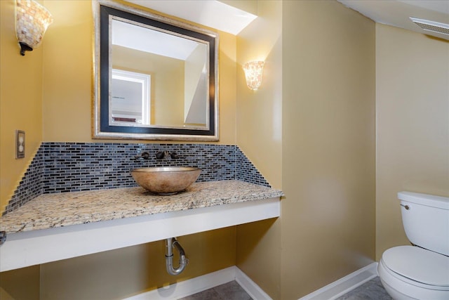 bathroom featuring vanity, visible vents, toilet, and tasteful backsplash