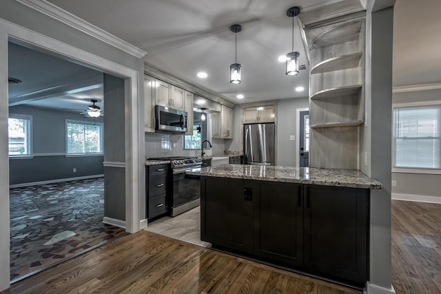 kitchen featuring a peninsula, ceiling fan, light stone counters, a sink, and stainless steel appliances