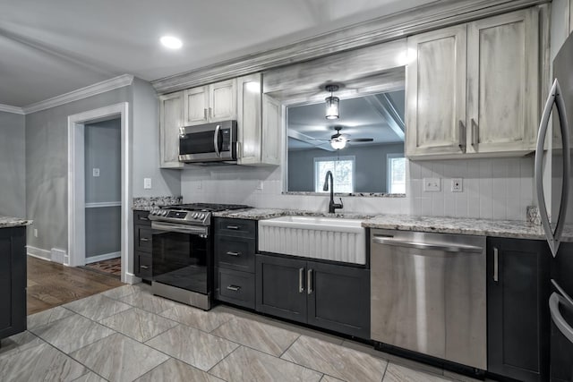 kitchen with decorative backsplash, a ceiling fan, appliances with stainless steel finishes, a sink, and ornamental molding