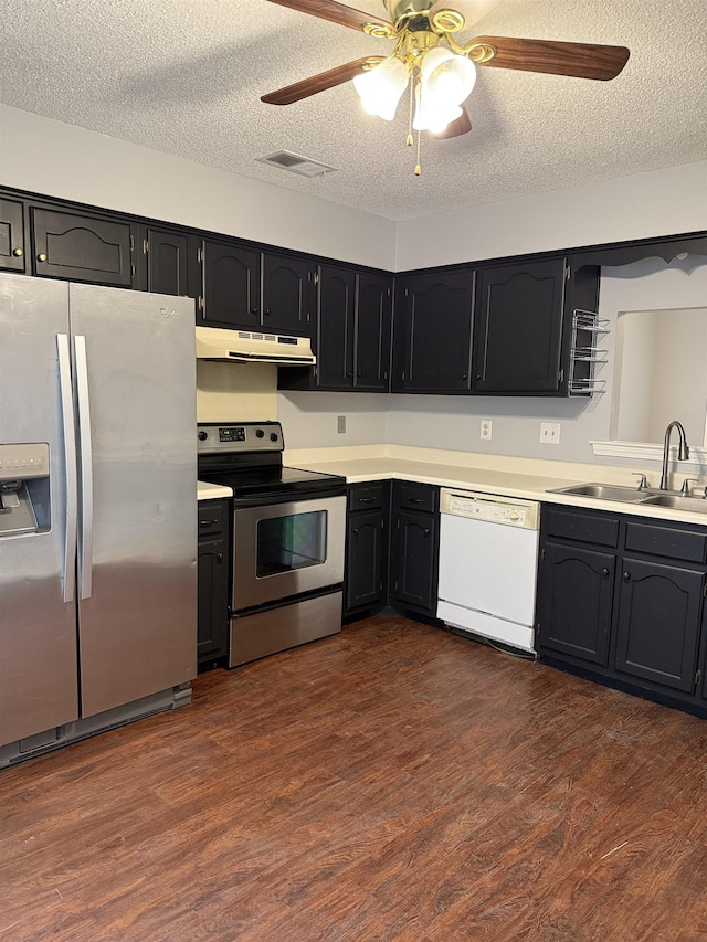kitchen with under cabinet range hood, stainless steel appliances, dark wood finished floors, and a sink